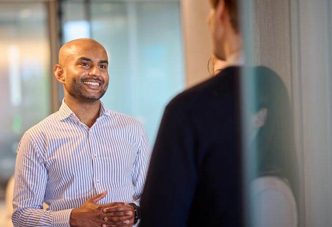 A man talking to another man in an office.